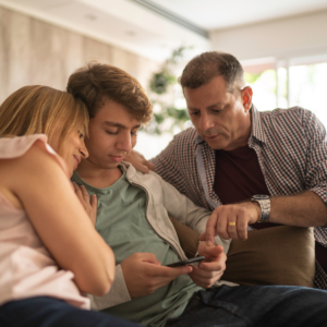 eine Mutter, ein Sohn, ein Vater sitzen nebeneinander