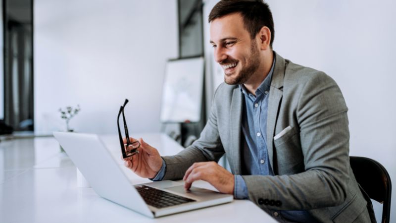 Mann vor Laptop lächelnd Verwaltungsunternehmen